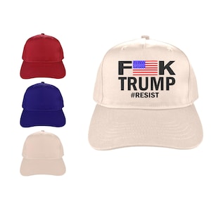 May include: Baseball caps in red, blue, and beige. A beige cap features the text "F*K TRUMP" with an American flag graphic and the hashtag "#RESIST". The caps are made of a durable fabric and have a curved brim.