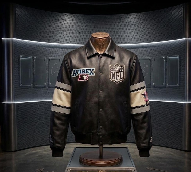 Peut inclure: Veste en cuir noire avec les logos "Avirex" et "NFL". La veste a des rayures blanches et grises sur les manches et une fermeture boutonn&eacute;e. La veste est pr&eacute;sent&eacute;e sur un mannequin.