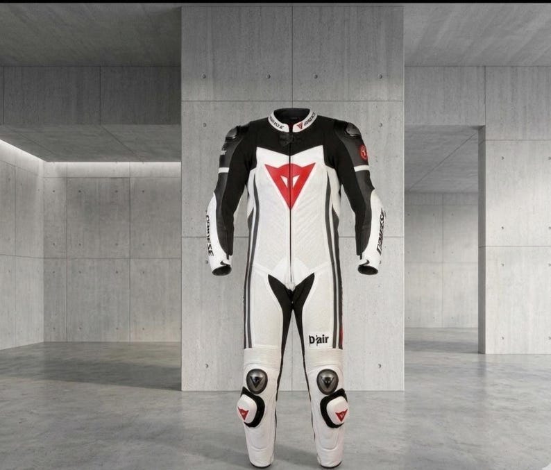 Puede incluir: Traje de carreras de motociclismo blanco y negro con un logotipo de tri&aacute;ngulo rojo en el pecho. El traje tiene detalles en negro en los hombros y los brazos, con protecci&oacute;n para rodillas y codos. La palabra "D'air" est&aacute; impresa en la pierna.