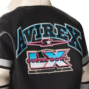 Peut inclure: Veste en cuir noire avec des d&eacute;tails blancs et gris. Le dos affiche le mot "AVIREX" en bleu et rose, ainsi que "SUPER BOWL LX" et "SAN FRANCISCO BAY AREA". La veste a un col blanc.