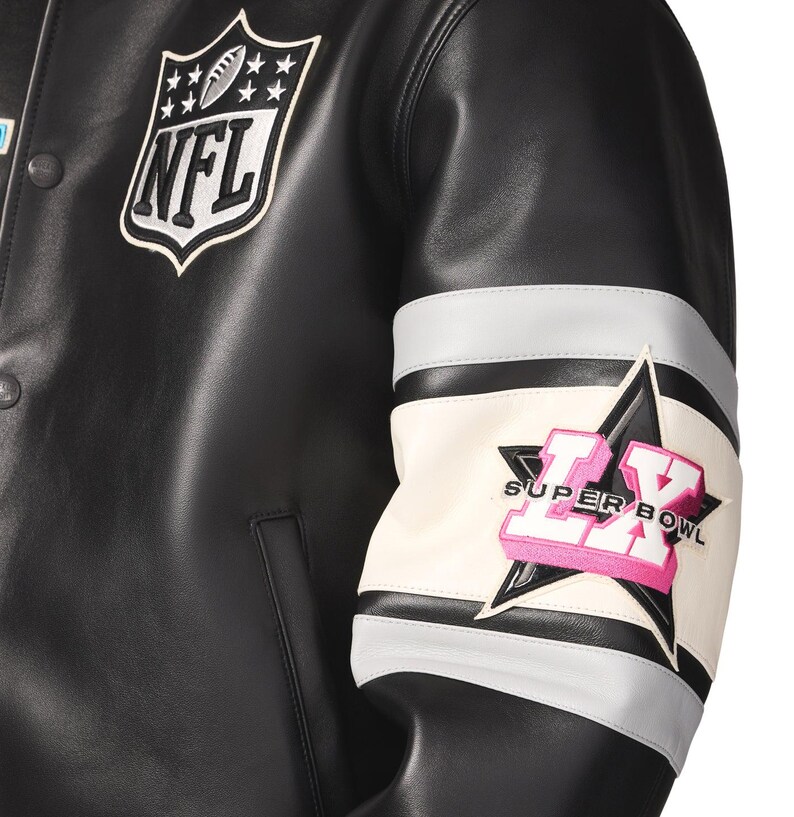 Peut inclure: Veste en cuir noire avec &eacute;cusson du logo NFL sur la poitrine. La manche pr&eacute;sente un motif blanc, gris et noir avec une &eacute;toile et le texte "SUPER BOWL LX" en rose.