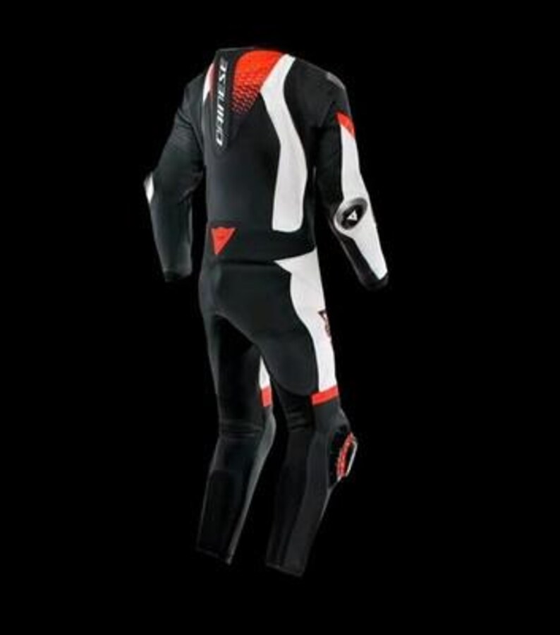 May include: Black and white motorcycle racing suit with red accents. The suit features a streamlined design with protective padding on the shoulders, elbows, and knees. The brand name "DAINESE" is visible on the back and chest.