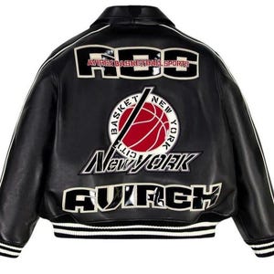Może przedstawiać: Czarna sk&oacute;rzana kurtka typu varsity z białymi i czerwonymi haftowanymi naszywkami na plecach. Napis głosi ABS AVIREX BASKETBALL SPORTS, BASKET NEW YORK CITY, NEW YORK oraz AVIREX. Posiada prążkowany kołnierz, mankiety i d&oacute;ł w białe paski.