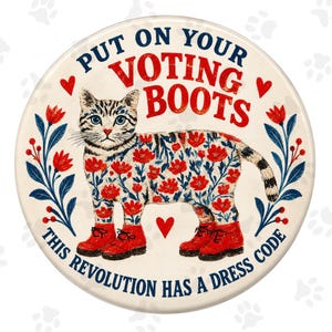Può includere: Un cartello decorativo rotondo con un gatto tigrato che indossa stivali rossi. Il corpo del gatto presenta un motivo floreale. Il testo recita: PUT ON YOUR VOTING BOOTS. THIS REVOLUTION HAS A DRESS CODE. Il design include cuori rossi e steli floreali blu.