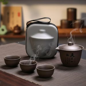 May include: A brown tea set with a teapot, three small cups, and a carrying case. The teapot has a lid and spout, with steam rising from it. The cups are round and sit on a brown mat. The carrying case is gray.