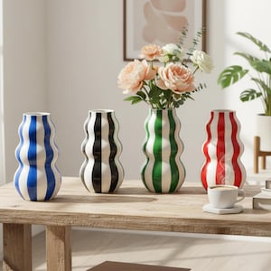 May include: A set of three ceramic mugs with a speckled, matte finish. The mugs are in shades of cream, light gray, and dark gray. Each mug has a simple, minimalist design, perfect for coffee or tea.