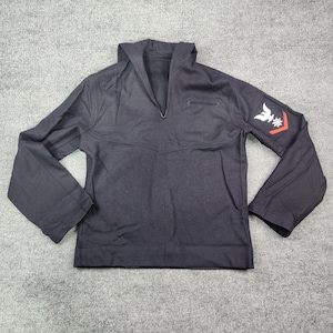 May include: A dark navy blue long-sleeve pullover shirt featuring a V-neck collar and a large flap. The left sleeve displays a white embroidered eagle emblem above a red chevron stripe, representing a military-style uniform top design.