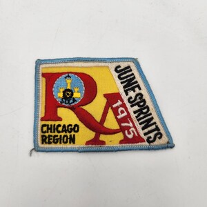 May include: A rectangular embroidered patch with a yellow background and a light blue border. It features a large red letter R, the text CHICAGO REGION, and JUNE SPRINTS 1975 in black and white. A small circular emblem with a yellow tower is visible.
