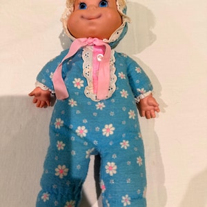 May include: A white ceramic mug with a black handle and the text "But First, Coffee" in a black, bold font. The mug is sitting on a wooden surface. The mug is approximately 4 inches tall.