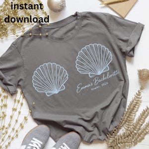 May include: Gray t-shirt with two light blue seashell graphics. The text "Emma's Bachelorette Miami, 2026" is printed on the shirt. The words "instant download" are in the top left corner.