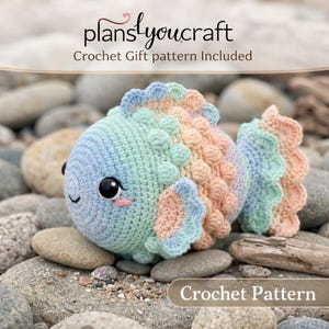 May include: A crocheted fish toy in pastel colors of blue, green, and peach, with large black eyes and a smiling expression. The text "plans you craft" and "Crochet Gift pattern Included" are visible. The words "Crochet Pattern" are also visible.