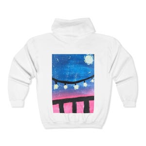 May include: White hooded sweatshirt with a night scene painting on the back. The artwork shows a blue sky, full moon, string lights, and a pink and black foreground. The sweatshirt has a drawstring hood and long sleeves.