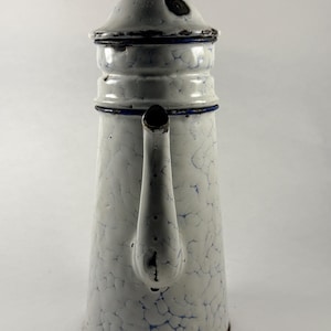 Peut inclure: Cafetière ancienne en émail blanc avec un motif craquelé bleu. La cafetière a un couvercle, un bec et une poignée. Le bord et les accents sont bleus. Un article de cuisine classique.