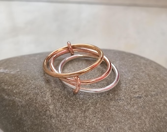 Anel com faixas entrelaçadas em três cores: ouro, prata e ouro rosa, conjunto feito à mão em metais mistos.