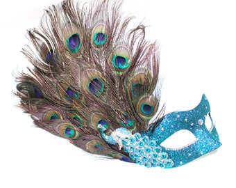 May include: A blue masquerade mask with peacock feathers and rhinestones. The mask is decorated with a peacock design and has a sparkly finish.