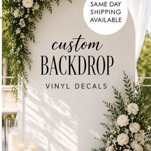 Può includere: Uno sfondo ad arco bianco con testo nero che recita custom BACKDROP VINYL DECALS. L'arco è decorato con fiori bianchi e fogliame verde negli angoli in alto a sinistra e in basso a destra, con candele bianche in cilindri di vetro.