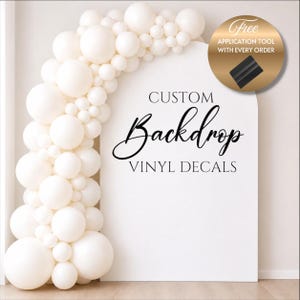 May include: A white arch-shaped backdrop with the words "CUSTOM Backdrop VINYL DECALS" in black script. A balloon garland in shades of white and cream arches over the top left. A gold circle with text and a black tool is in the upper right.
