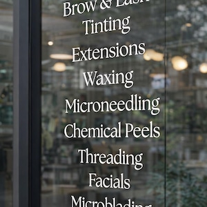 May include: A glass door with white text listing beauty services: Brow & Lash Tinting, Extensions, Waxing, Microneedling, Chemical Peels, Threading, Facials, and Microblading. The BIZ SIGNZ logo is in the bottom left corner.