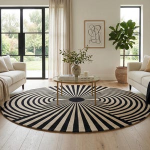 May include: A living room scene featuring two cream-colored sofas, a round black and white patterned rug, and a glass-topped coffee table. The room has hardwood floors, sheer curtains, and a large window overlooking a garden.