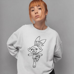 May include: White sweatshirt featuring a black outline drawing of a cartoon rabbit in motion. The rabbit has large ears and is wearing a shoe. The sweatshirt is a solid white color.