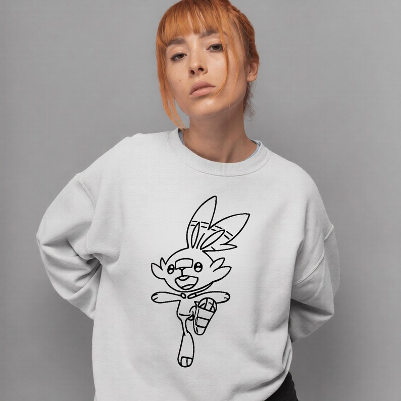 May include: White sweatshirt featuring a black outline drawing of a cartoon rabbit in motion. The rabbit has large ears and is wearing a shoe. The sweatshirt is a solid white color.