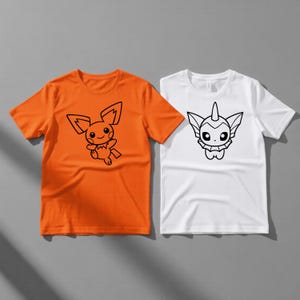 May include: Two short-sleeved t-shirts. One is orange with a black cartoon character design. The other is white with a different black cartoon character design. Both shirts are on a gray background.