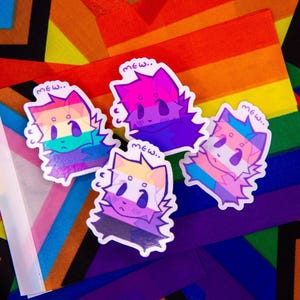 May include: Four cat-shaped stickers with pride flag designs and the word "mew" above each. The stickers are on a background of rainbow and geometric patterns. The stickers feature the colors of the LGBTQ+ pride flag, bisexual flag, transgender flag, and pansexual flag.