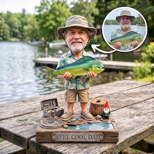 May include: A custom bobblehead figurine of a man with a beard wearing a tan bucket hat and a tropical print shirt, holding a large green and yellow mahi-mahi fish. The base features a tackle box, a fishing net, a wicker basket, and a garden gnome.