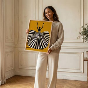 May include: A rectangular framed art print featuring a stylized illustration of a figure with arms raised, wearing a voluminous dress with bold black and white vertical stripes against a solid mustard yellow background.