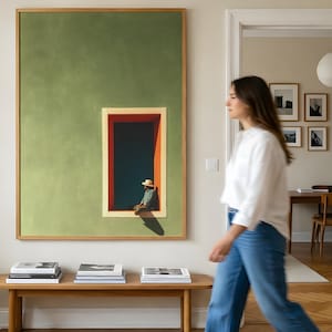 May include: A large rectangular wall art piece featuring a solid sage green background with a centered vertical window frame in red and orange. Inside the frame, a figure wearing a straw hat sits in a dark blue space with a sharp shadow cast below.