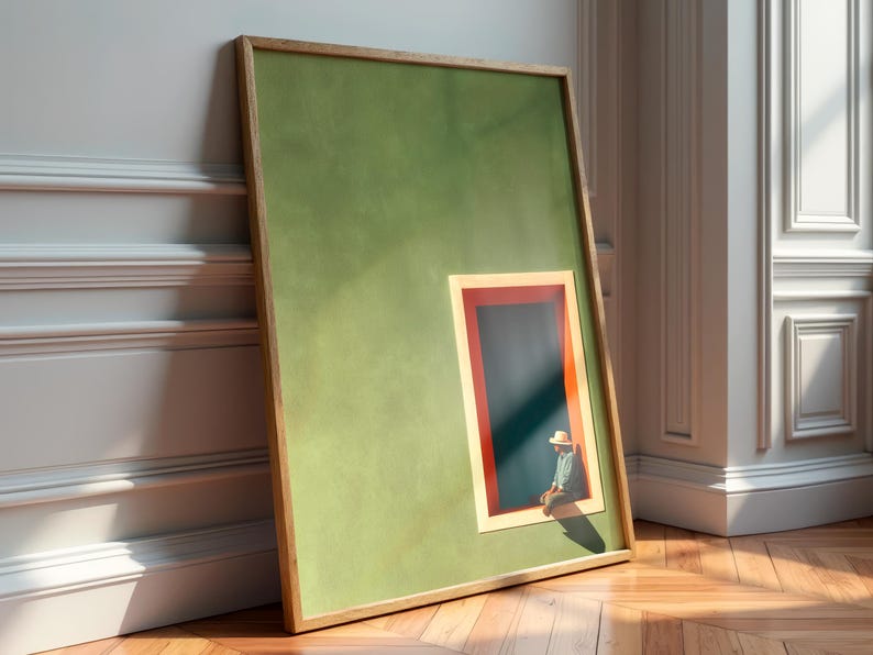 May include: A framed rectangular wall art piece featuring a solid olive green background with a smaller inset rectangular window. The window has a red and cream border and contains a dark blue interior with a small figure wearing a hat sitting inside.