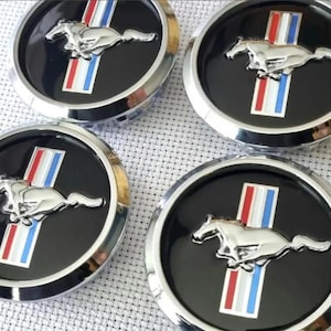 May include: Four black and silver car emblems featuring the iconic running horse logo. Each emblem has a silver border, a black center, and a vertical stripe with red, white, and blue colors.