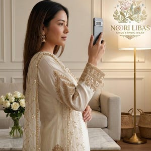 May include: A woman in a cream-coloured ethnic wear outfit with gold embroidery and embellishments. The outfit includes a long-sleeved top and a matching scarf. The image also shows the brand logo "NOORI LIBAS GIRLS ETHNIC WEAR".