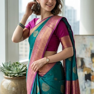 May include: A teal sari featuring a wide magenta border with intricate gold metallic patterns. The fabric is adorned with repeating gold leaf-shaped motifs throughout. It is paired with a solid magenta short-sleeved blouse with gold trim.