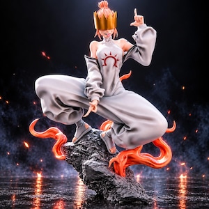 May include: A dynamic anime-style figurine of a character with pink hair wearing a gold crown, a light gray high-neck outfit with a red sun emblem on the chest, and sandals. The figure is posed in a crouched stance atop a dark, jagged rock base.