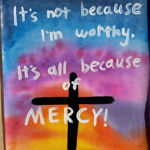 May include: A canvas painting with a colorful sunset background, a black cross, and white text that reads "It's not because I'm worthy. It's all because of MERCY!"