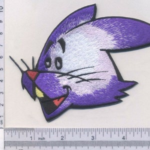 May include: Purple and white embroidered iron-on patch of a cartoon rabbit with a big smile and large eyes.