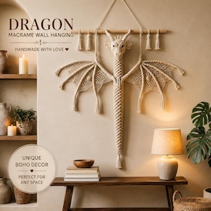 May include: A cream-colored macrame wall hanging shaped like a dragon with intricate knotted wings and a long tail, suspended from a horizontal wooden rod with decorative tassels. The text DRAGON MACRAME WALL HANGING is visible above.