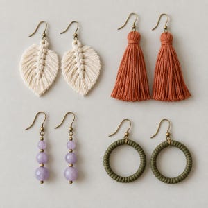 May include: Four pairs of earrings featuring diverse designs: cream-coloured macrame leaf shapes, rust-coloured thread tassels, lavender faceted bead dangles, and olive green circular hoops wrapped in cord, all attached to bronze-toned metal hooks.
