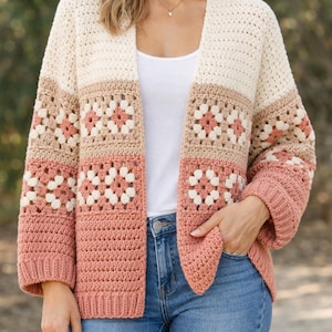 May include: A cream, tan, and rose-colored crochet cardigan. The open-front sweater features a granny square design with a ribbed cuff and hem. The sleeves are three-quarter length.