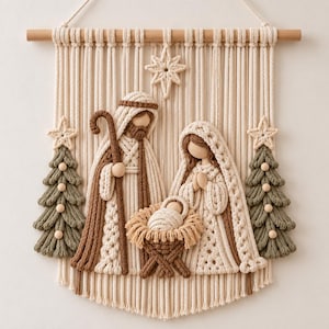 Könnte beinhalten: Ein Makramee-Wandbehang mit einer Krippenszene, die Josef, Maria und das Jesuskind in einer Krippe zeigt. Das Design umfasst zwei salbeigrüne Tannenbäume, einen Stern darüber und einen Holzstab oben, alles gefertigt aus cremefarbener und brauner Kordel.