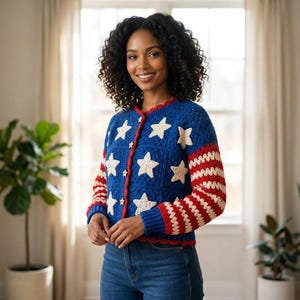 May include: A blue crochet cardigan with white star and red and white striped sleeve designs. The cardigan has a red trim and is buttoned up. The garment is worn with blue jeans.