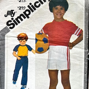 May include: A Simplicity sewing pattern for a child's red and white soccer uniform. The pattern includes a red short-sleeved shirt with white stripes on the sleeves, white shorts with red stripes down the sides, and white socks. The pattern is sized for stretch knits only. The pattern is $2.50.