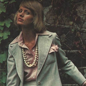 May include: A Vogue Americana Anne Klein sewing pattern envelope featuring a light gray blazer and skirt suit with a pink collared shirt, layered bead necklace, and a matching illustration of a navy blazer with a white skirt and pink shirt.