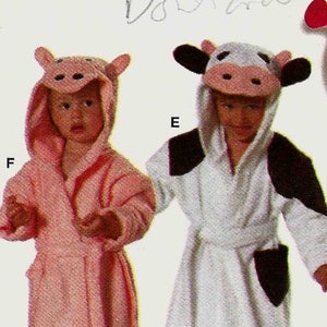 May include: A sewing pattern for baby accessories, including cow and pig-themed bathrobes and stuffed animals. The pattern features a pink pig with a heart, a cow-themed robe, and a warning about flammable fabrics.