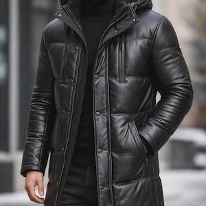 Könnte beinhalten: Eine schwarze Lederjacke mit Kapuze und Steppdesign. Die Jacke hat einen Reißverschluss, Knöpfe und Taschen. Das Model trägt einen schwarzen Rollkragenpullover und dunkle Jeans.