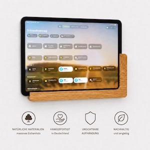 Könnte beinhalten: Eine Wandhalterung aus hellbraunem Eichenholz, in der ein Tablet mit einer Smart-Home-Steuerungsoberfläche steckt. Darunter befinden sich vier kreisförmige Symbole mit dem Text: Natürliche Materialien, Handgefertigt in Deutschland, Unsichtbare Aufhängung, Nachhaltig und langlebig.