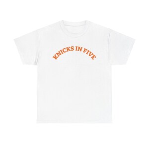 Op de afbeelding: Een wit T-shirt met korte mouwen en de tekst KNICKS IN FIVE in een oranje, gebogen lettertype in collegestijl op de borst gedrukt. Het kledingstuk heeft een ronde hals en een standaard pasvorm, wat zorgt voor een strakke uitstraling.