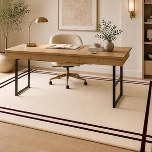 Könnte beinhalten: Ein rechteckiger Teppich mit cremefarbener Basis und einem dunkelbraunen Randdesign, das aus zwei parallelen Linien besteht, die sich an jeder Ecke kreuzen. Der Teppich liegt unter einem Schreibtisch aus Holz mit schwarzen Metallbeinen und einem Drehstuhl.