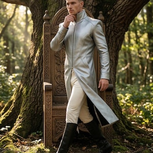 May include: A silver long coat with a high collar and a full-length zipper. The coat is paired with cream-colored pants and black knee-high boots. The background features a carved wooden chair and a large tree in a forest setting.